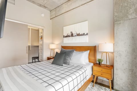 Cozy bedroom featuring wooden furniture, a city skyline artwork, and a soft color palette.