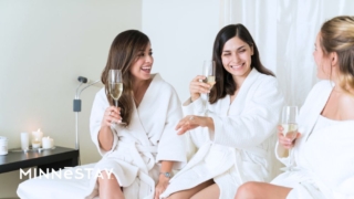 Guests experiencing at top tiered spa in Minneapolis recommended by MINNeSTAY with three ladies in robes with champaign