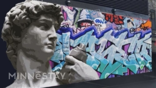 mural in the North Loop by local artist. head of famous sculpture of David spray painting graffiti art on the wall behind him.