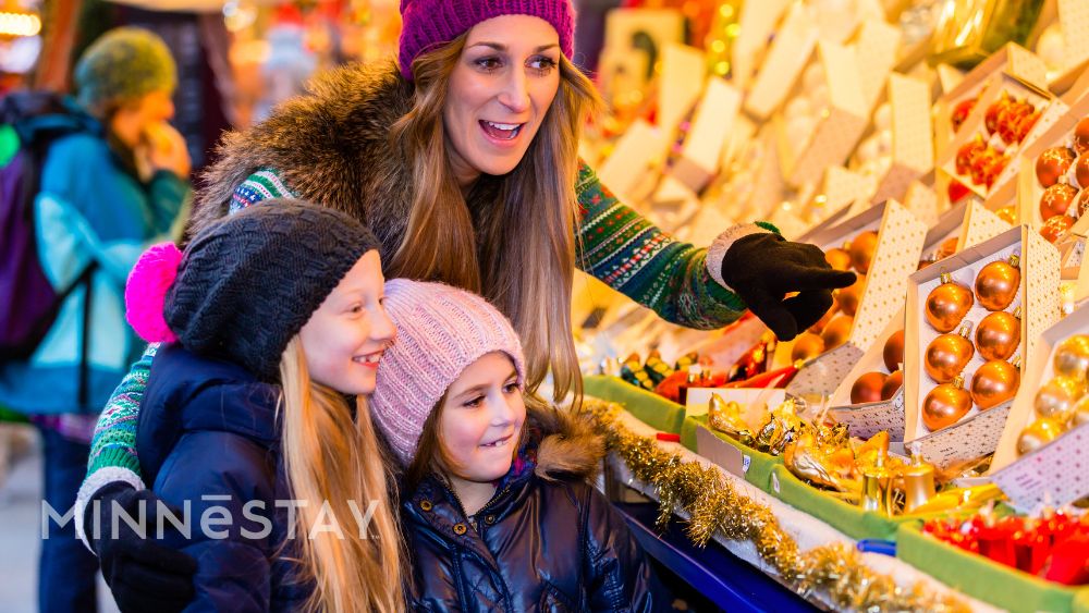 People at Minneapolis winter market with warm coats and hats looking at Christmas Ornaments in the Window